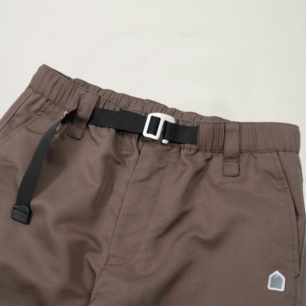 Brown pants with a black belt and small logo on a beige background