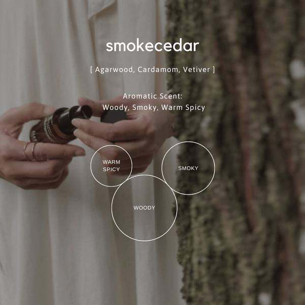 Person holding a container with smokecedar product, surrounded by natural elements.