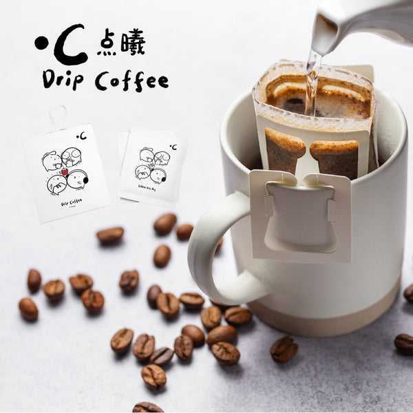 Drip coffee being poured into a white mug with coffee beans and a 'Drip Coffee' brand card in the background.