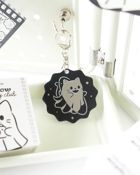 Black and white cat-themed keychain on a white surface with a small card.