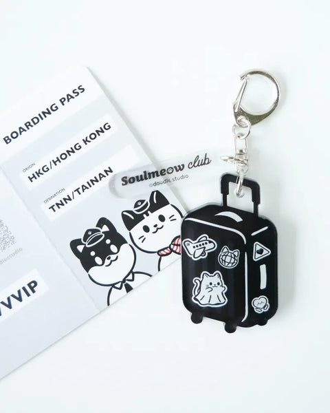 Keychain in the shape of a black suitcase with white accents, featuring cartoon cat designs, on a white background.
