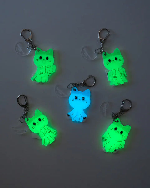 Glowing cat-shaped keychains on a gray background