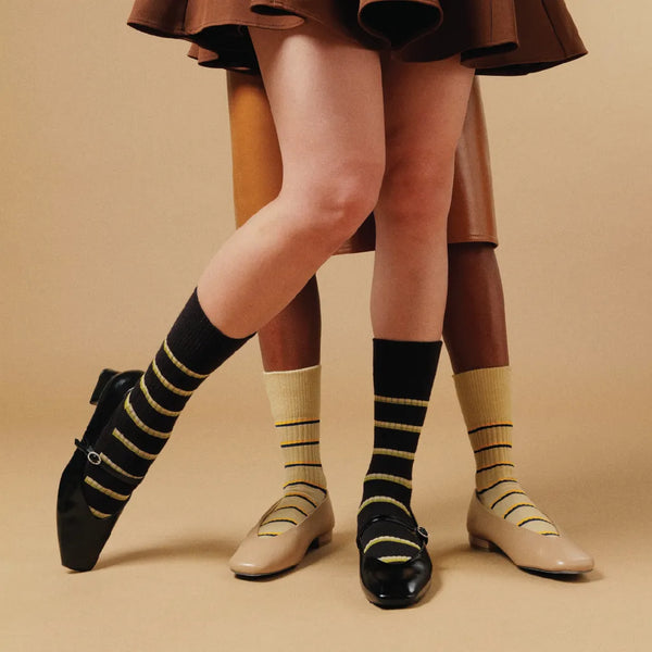 Person wearing striped socks and shoes on a beige background