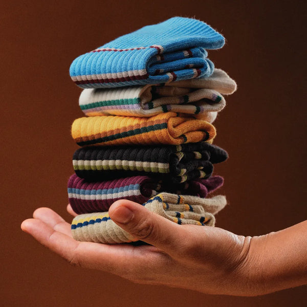 Stack of colorful socks held in a hand against a brown background