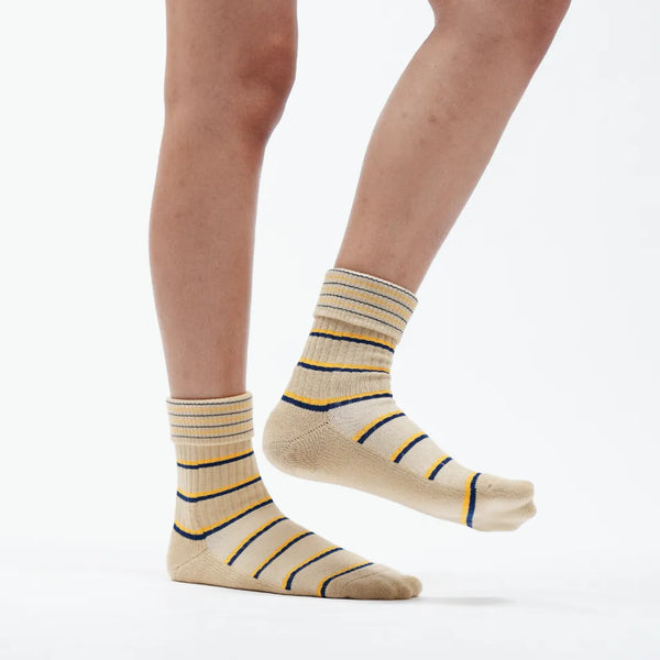 Beige socks with blue stripes worn by a person on a white background