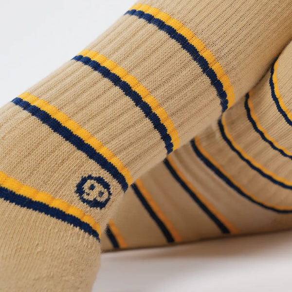 Close-up of beige socks with yellow and blue stripes on a light background