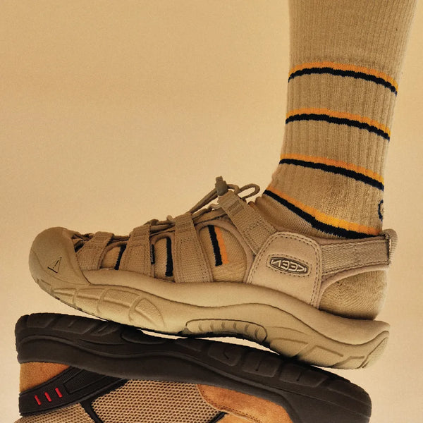 Tan sandal worn with a striped sock on a beige background