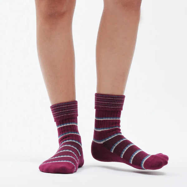 Purple striped socks worn by a person on a white background