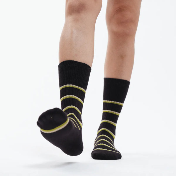 Black socks with yellow stripes worn by a person on a white background