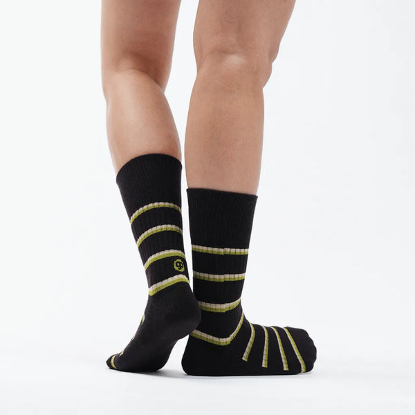 Black socks with yellow stripes worn by a person on a white background