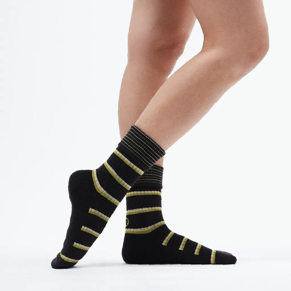 Black socks with yellow stripes worn by a person on a white background