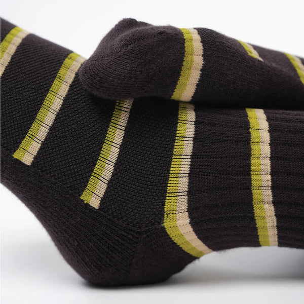 Close-up of a black sock with green and beige stripes on a white background