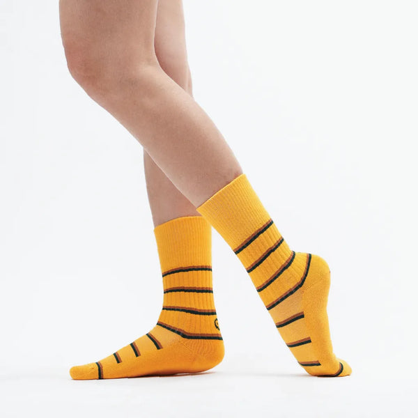 Yellow socks with black stripes worn by a person on a white background