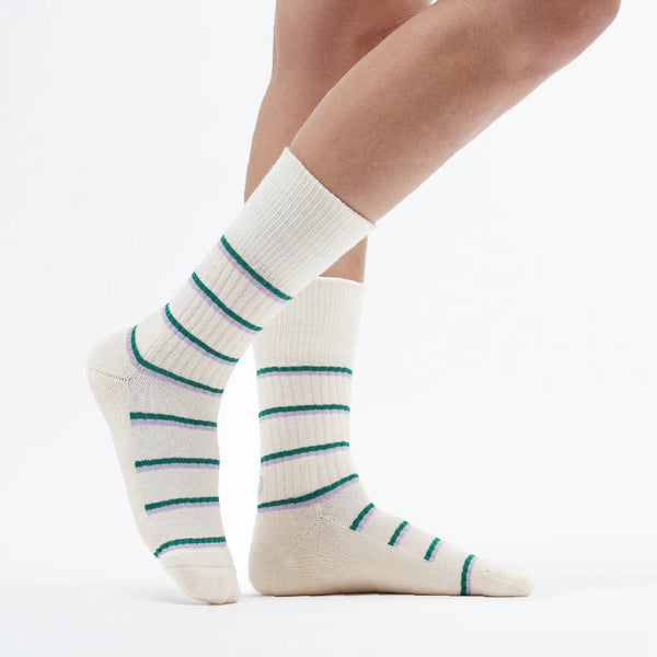 White socks with green stripes worn by a person on a white background