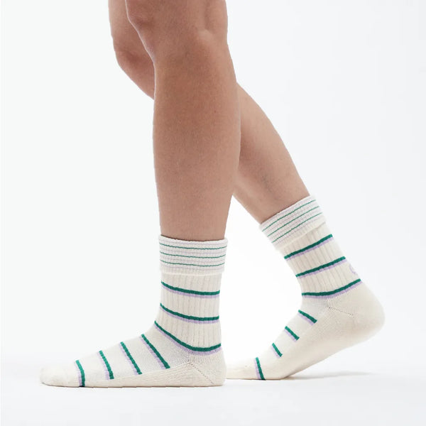 White socks with green stripes worn by a person on a white background