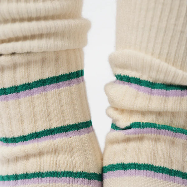 Close-up of beige socks with green and purple stripes on a white background