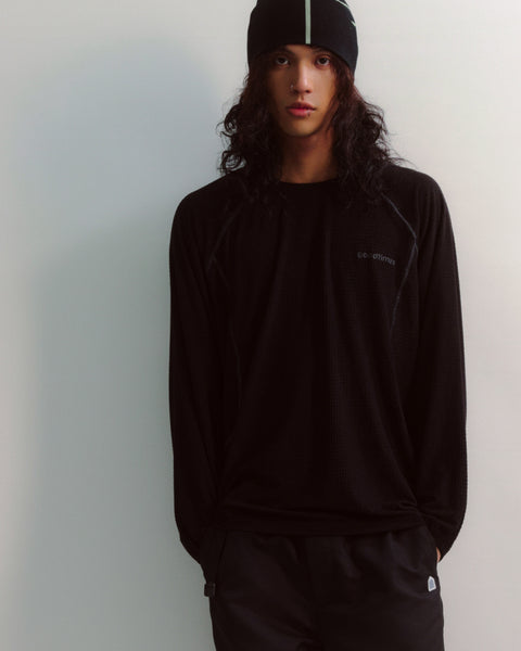 Person wearing a black outfit with a logo on a plain background