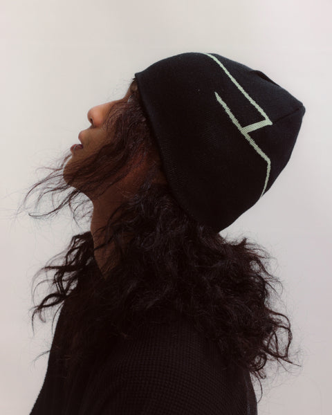 Person wearing a black beanie with a white logo on a white background