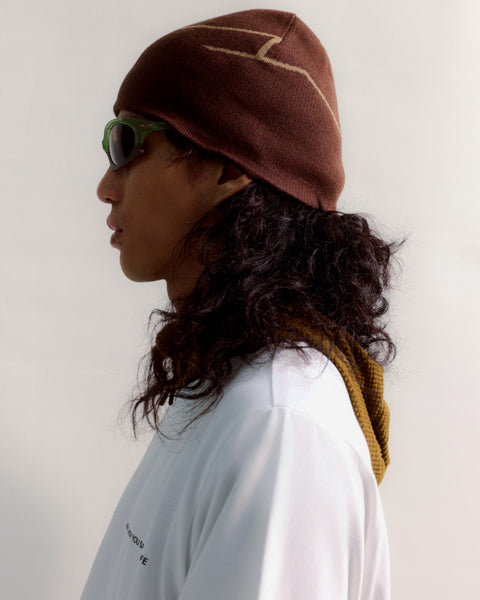 Person wearing a brown beanie and sunglasses with a white background