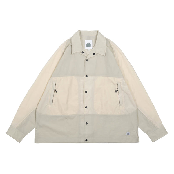 Beige and cream color-blocked shirt with black buttons on a white background
