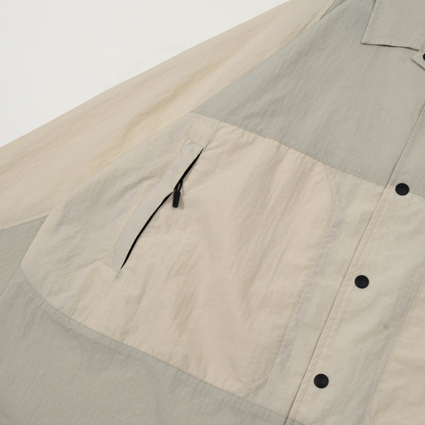 Close-up of a shirt with color-blocked design and button details on a light gray background