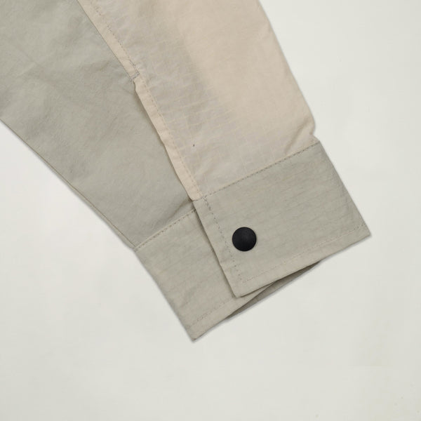 Close-up of a beige fabric with a button on a light gray background