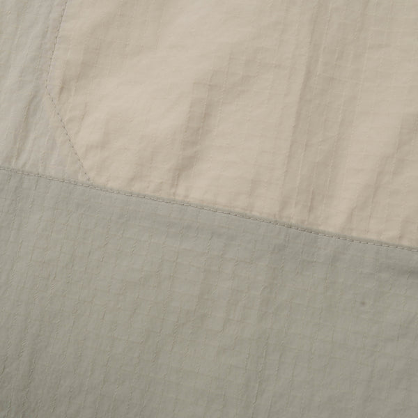 Close-up of beige and gray fabric with a visible seam.