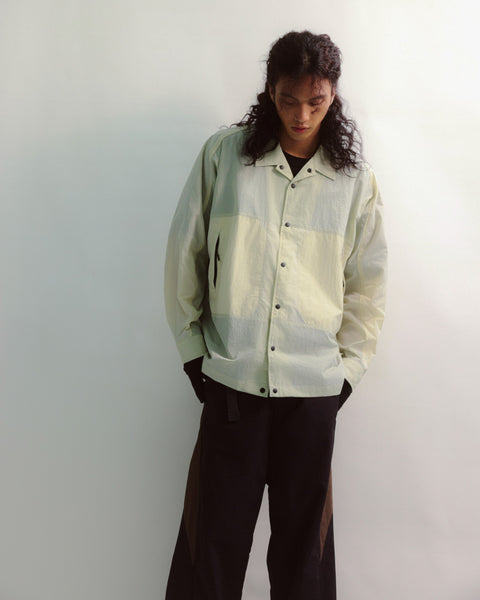 Person wearing a light green and white checkered shirt against a plain background