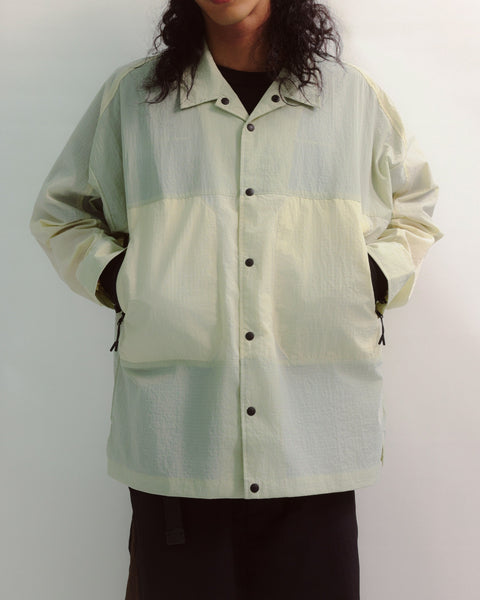 Person wearing a light green and white checkered jacket on a plain background