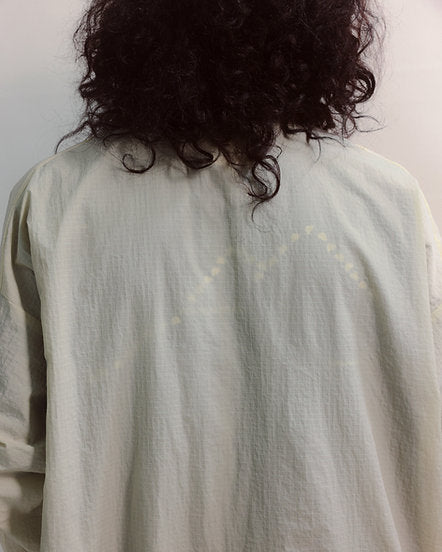 Person wearing a light green shirt with subtle patterns, facing away from the camera.