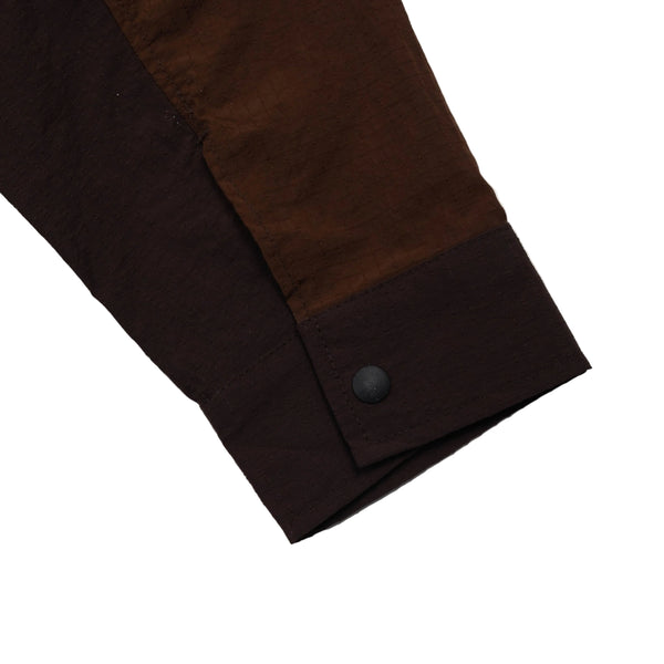 Close-up of a brown fabric with a button on a light gray background