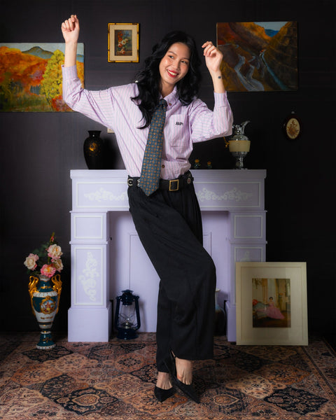 Woman posing with arms raised in a room with a fireplace and artwork on the walls.