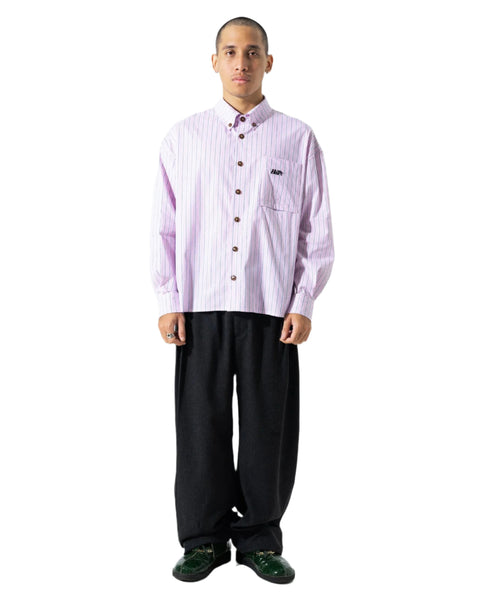 Person wearing a light purple checkered shirt with a brand logo, black pants, and green shoes on a white background
