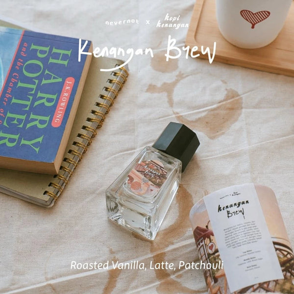 Perfume bottle with 'Harry Potter' book and cup on a textured surface, featuring 'Kenangan Brew' branding.