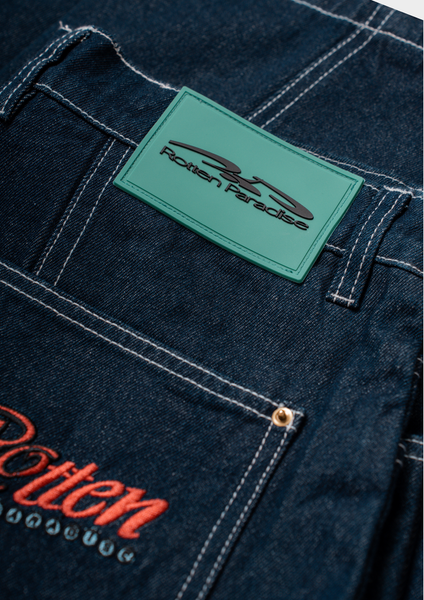 Close-up of a dark blue denim jacket with 'Rotten Paradise' branding on a green label and red text.