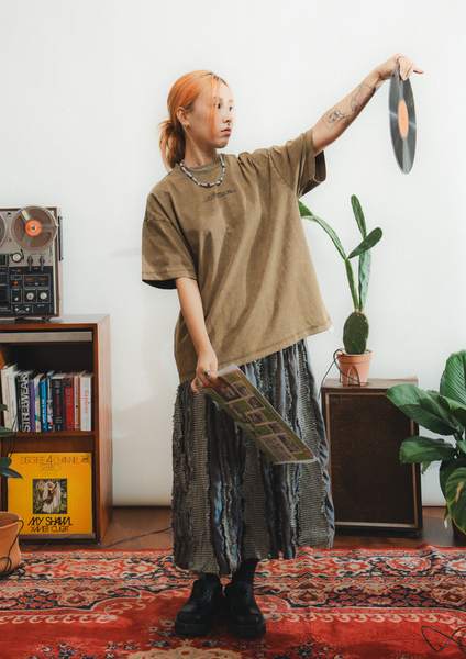 Person holding vinyl records in a room with record player and plants