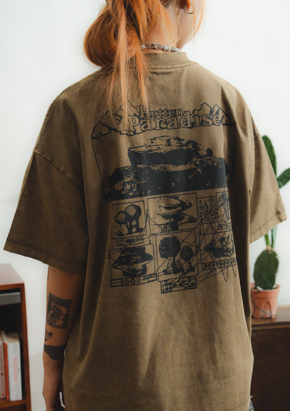 Person wearing a brown t-shirt with graphic design on the back, standing indoors.