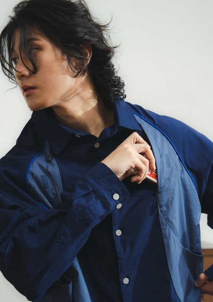 Person wearing a blue jacket over a black shirt against a white background