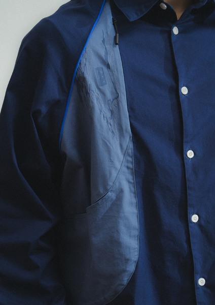 Close-up of a blue jacket with a white button on a plain background