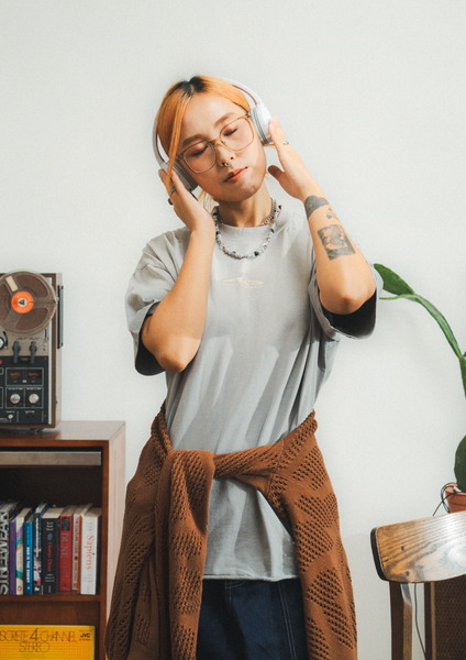 Person wearing headphones in a room with a record player and books.