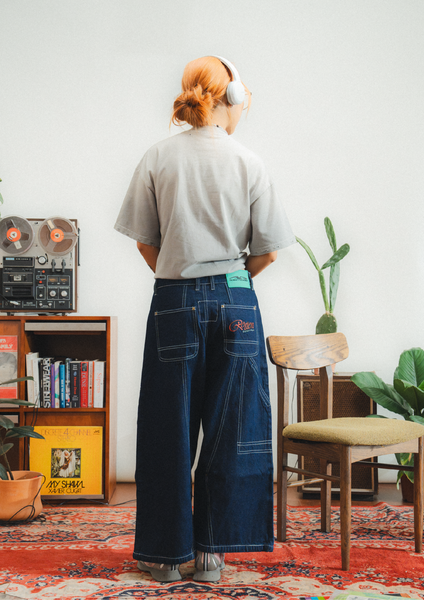 Person wearing headphones and a light shirt in a room with a vintage radio and books.
