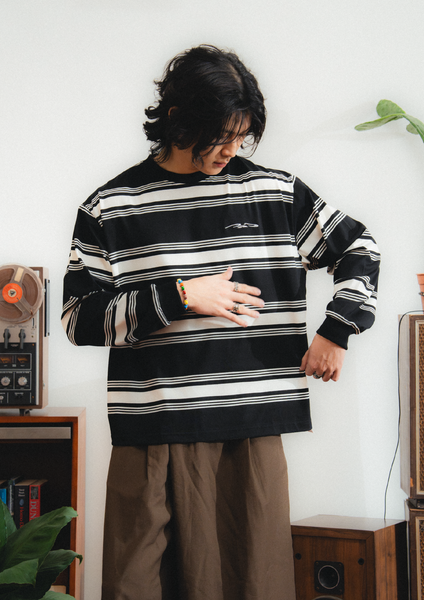 Person wearing a black and white striped sweater with a graphic design, standing in a room with vintage equipment.