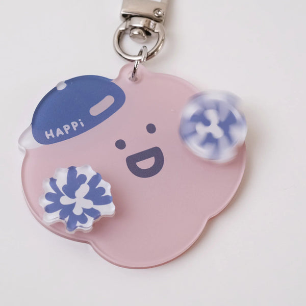 Pink keychain with a face design and blue accents on a white background