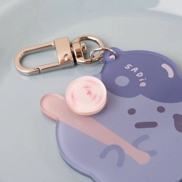 Keychain with a cartoon character design on a light blue background