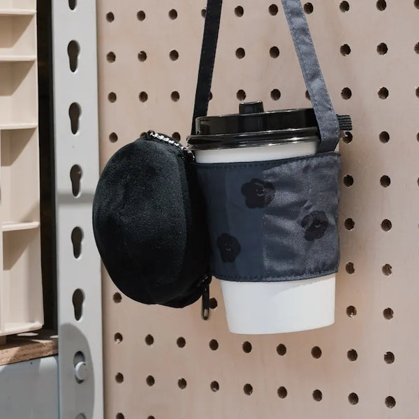 Coffee cup with a floral patterned sleeve attached to a pegboard.