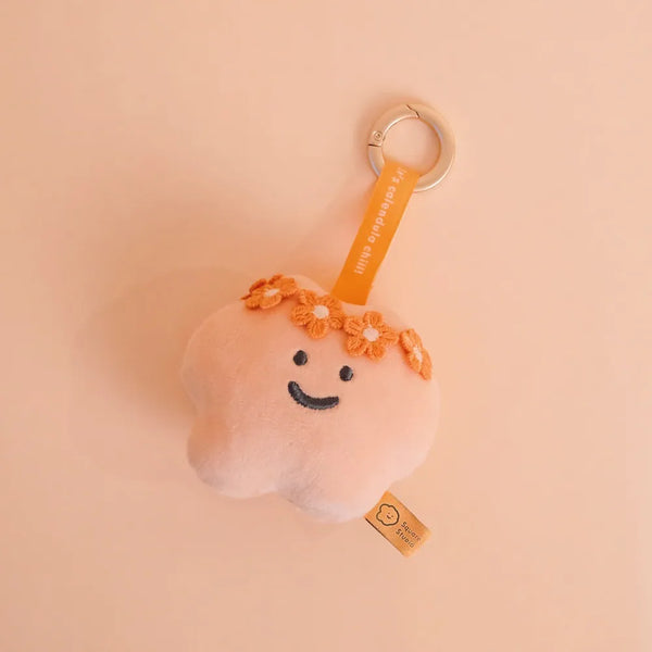 Plush keychain with a smiling face and orange hair on a beige background