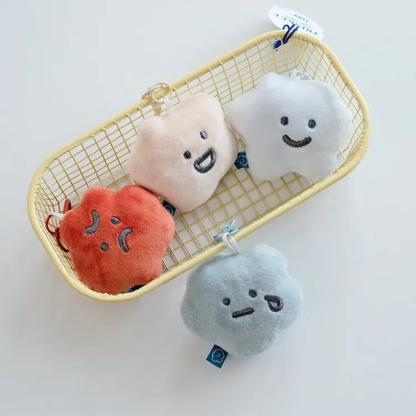 Plush toys shaped like a heart, square, circle, and triangle with smiling faces in a yellow basket on a white background.