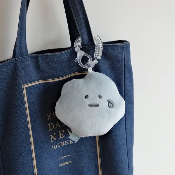 Plush keychain attached to a blue tote bag with a visible brand name.