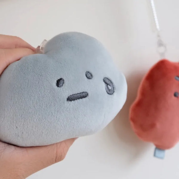 Plush toys shaped like a blue heart and a red circle with faces on a white background