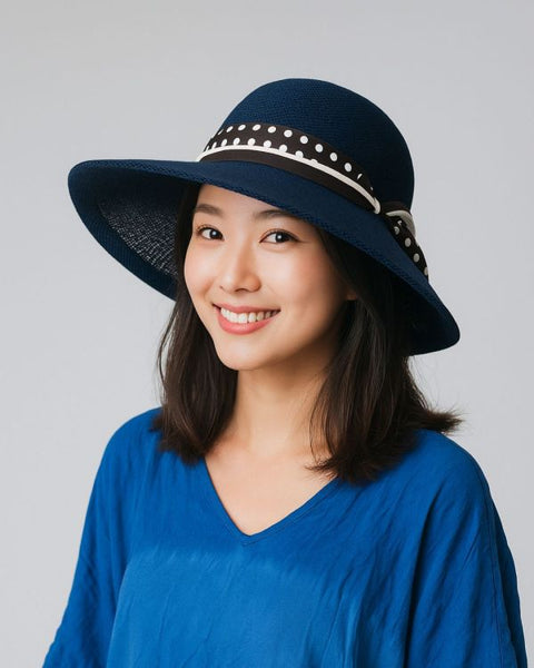 Woman wearing a navy blue sun hat with a decorative band on a gray background